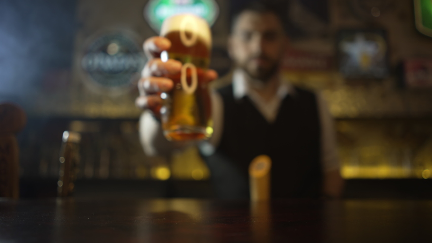 The bartender puts a glass of unfiltered beer on the bar. Slow motion video of the bartender. Beer pub party. | Shutterstock HD Video #1072969664