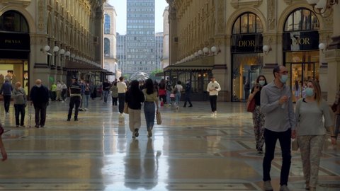 People in protective masks. tourists and local residents of the city in the gallery Vittorio Emanuele 2. Crowds of people. Shopping. Opening borders in Europe. Epidemic. Milan, Italy - May 2021: 
