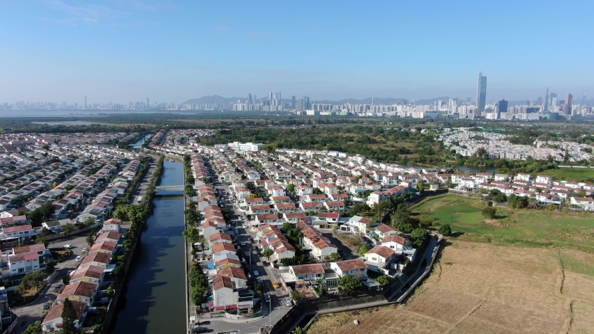Hong Kong and Shenzhen border line over Hong Kong rural houses with Shenhzen skyline in the horizon, Aerial view.