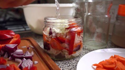 Pouring Brine Into A Jar With Chopped Vegetables. Making Pickled White Cabbage At Home. close up