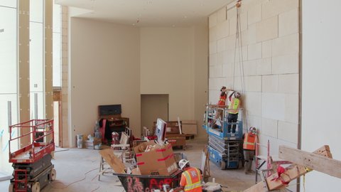 San Diego, California, USA - October 7, 2019: Stonemasons lifting and installing heavy limestone tiles to finish a wall in a new theater lobby.