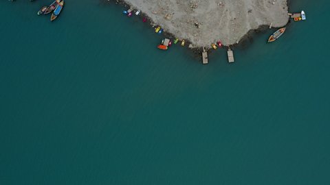 Aerial top view over Attabad lake shore with colorful boats and houses