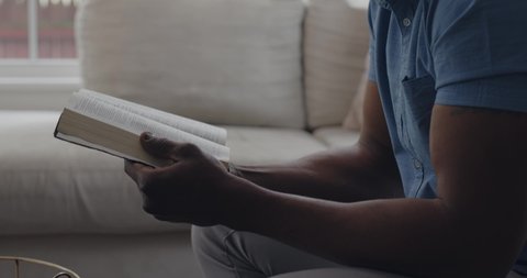 Black man reads Bible verse and looks up thoughfully contemplating, Profile View