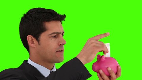 Dark-haired businessman saving up money against a green screen