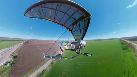 Bright rainbow colored hang glider lands on the green field. Extreme sport onboard footage