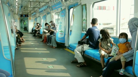 Jakarta, Indonesia - May 2021: People wear masks on mrt train journey  to protect against covid-19 virus during pandemic.

