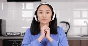 Portrait of an attractive asian girl in headphones talking to the camera. Online call. Distance learning. Quarantine.
