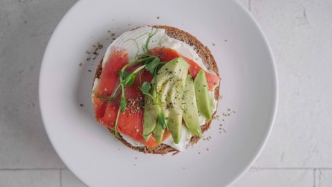 Breakfast toast with cream cheese, salmon and avocado, white background, top view.