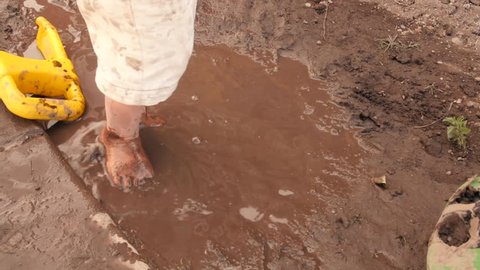 A little boy plays in a mud puddle and gets very dirty