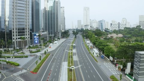 JAKARTA - Indonesia. May 18, 2021: Aerial view of quiet traffic on Sudirman street with skyscrapers during coronavirus quarantine in Jakarta city. Shot in 4k resolution from drone flying forwards