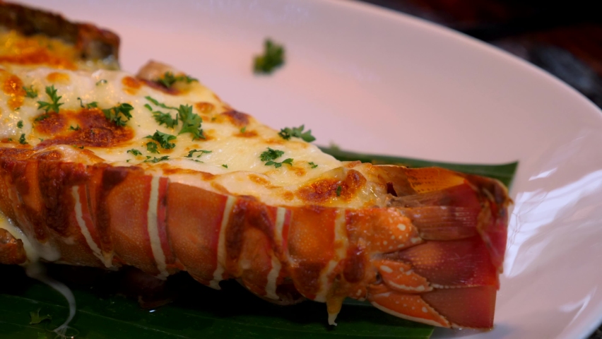 Close-Up of Grilled Lobster Meal with Herbs and Baked Cheese on Dinner Plate. Luxurious Restaurant with Fresh Seafood Menu. Eating Freshness Lobster Stuffed with Cream and Cheese. Gourmet Food. 4k | Shutterstock HD Video #1073020121
