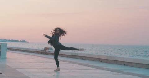 Young beautiful ballet woman is dancing on seaside, beach. Ballerina with ocean, sunset time. Healthy lifestyle, freedom and dance performance concept. 