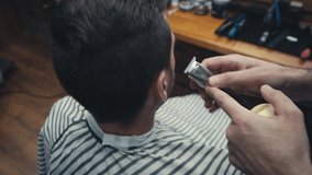 Barber using trimmer and brush on man in barbershop