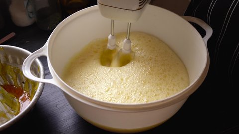 Baker mixing homemade cake flan mixture with electric whisk