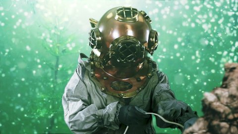 A deep sea diver working on the sea bed floor. The vintage navy diver's helmet is copper and brass providing air for breathing under water in the ocean