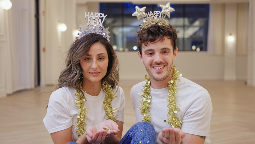 Young Couple Blow Glitter at Camera in New Years Crowns, Slow Motion Closeup
