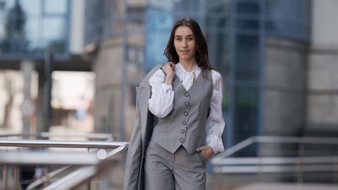 Fashionable young woman in a business suit with a jacket in her hands posing stylishly