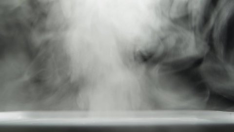 Abstract white smoke on a black background. White steam moves on a dark background close-up. 4K UHD