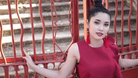 Beautiful Asian Woman In Red Suit Pose At Red Metal Fence , Slow Motion
