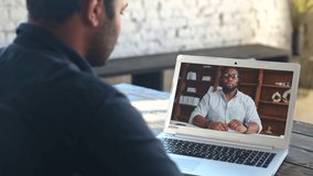 Two male diverse colleagues talks via video call. Indian man using laptop computer for virtual meeting with African-American male coworker, online tutoring