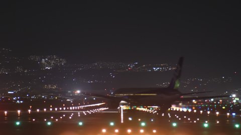 OSAKA, JAPAN - APRIL 10, 2018: Airport runway at night hour, short time lapse shot. Passenger plane landing and move to terminal, other airliner taxiing to airfield and take off