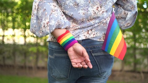 Asian lady wearing blue jean jacket with rainbow color flag, symbol of LGBT pride month celebrate annual in June social of gay, lesbian, bisexual, transgender, human rights.
 