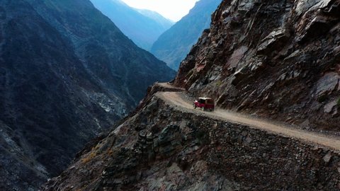 Old 4x4 Jeep Driving On Side Of The Mountain Towards Fairy Meadows In Pakistan - aerial drone shot