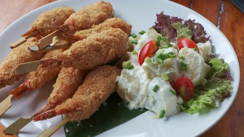 shrimp tempura with side potato salad on a white plate turning around
