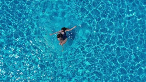 Drone view of couple relaxing, swimming in the pool. Two people enjoying summer holidays, weekend