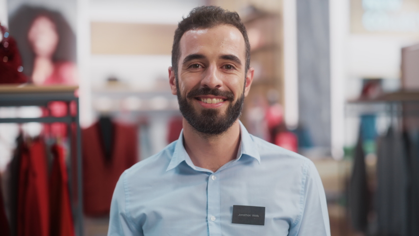 Portrait of a Happy Handsome Store Assistant in Blue Shirt Smiling and Posing for Camera at Clothing Store. Small Business Owner in a Role of a Businessman or Sales Manager. | Shutterstock HD Video #1073069234
