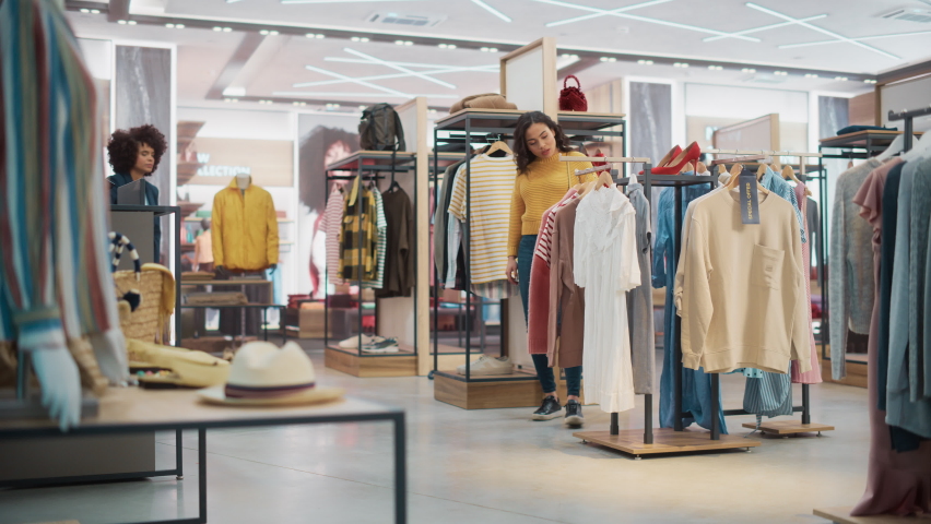 Customers Shopping in Modern Clothing Store, Retail Sales Associate Assists Client. Diverse People in Fashionable Shop, Choosing Stylish Clothes, Colorful Brand Designs, Quality Sustainable Materials. Royalty-Free Stock Footage #1073069255