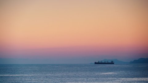 Evening seascape with cargo container industrial ship anchored waiting for entering Carboneras port in Almeria, Spain. Mediterranean sea coast. Logistic shipping concept.