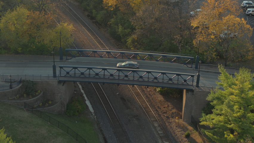 Cars cross a bridge over railroad tracks in Kirkwood in St. Louis, Missouri at golden hour in Autumn.