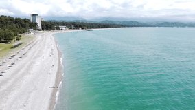 Aerial video from a drone of a beautiful seascape overlooking the Black Sea beach coast in Abkhazia in the city of Pitsunda. Resort background with beautiful turquoise colored sea.