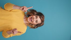 Vertical video Happy young woman blogger close up dancing hands up on copy space for advertising moving rhythmically to music curly hair share video to social media, stories on blue background banner. - Powered by Shutterstock - Get 15% off with code: PIKWIZARD15