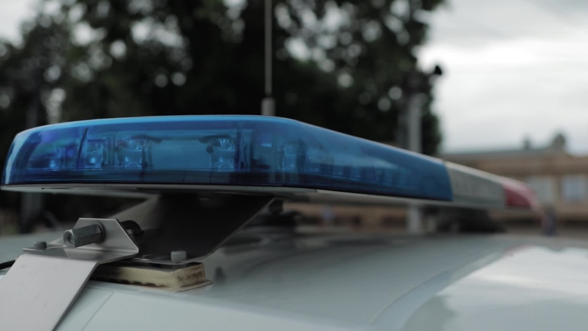 A police officer flashes a light on the roof of a patrol car. The police car flashes red and blue. Royalty-Free Stock Footage #1073084114