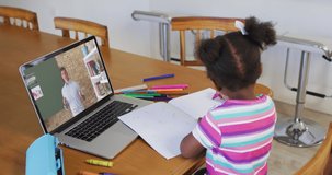 African american girl doing homework while having video call with male teacher on laptop at home. distance learning and online education concept