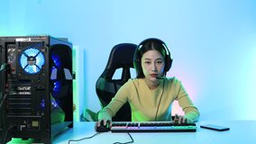 Young Asian beautiful woman Pro Gamer having live stream and playing in Online Video Game. Professional asian gamer girl leisure game in neon light room at home.