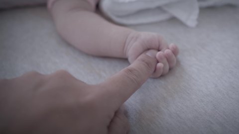 Parent holding newborn hand. close up. family and home concept.