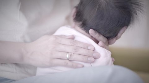 mother patting adorable newborn son massaging back