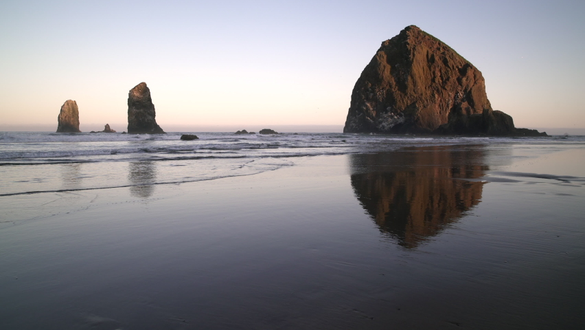Beach Dawn Haystack Rock Cannon Beach 4K UHD. Sunrise at Haystack Rock in Cannon Beach, Oregon as the surf washes up onto the beach. United States.
 Royalty-Free Stock Footage #1073098808