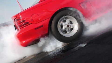 Red car. The wheel rotates with smoke