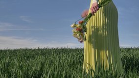 Woman hold beautiful flowers on green wheat field in spring 