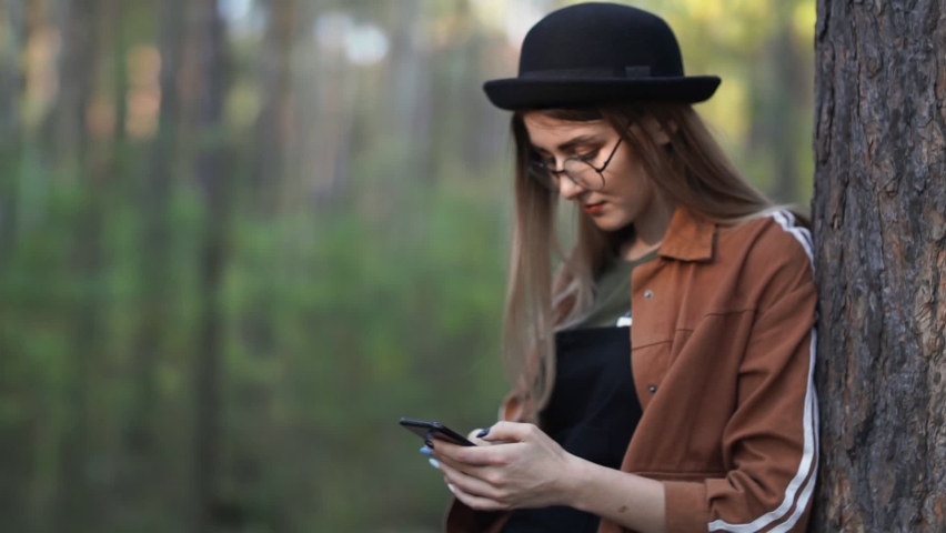 Portrait of a teenage girl with a smartphone in her hands, resting in the park.