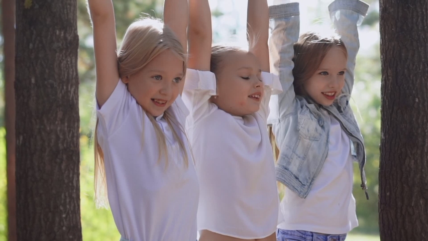 Three young girls are playing who will hang more on the bar. On open air