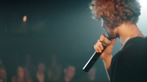CU Portrait of young Caucasian male comedian performing his stand-up monologue on a stage of a small venue. Shot with ARRI Alexa Mini LF with 2x anamorphic lens