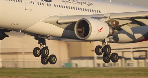 Melbourne, Australia - May 22, 2021: Close up view of Qantas Airbus A330 airliner airplane landing gear as it touches down on the runway during landing at Melbourne Airport, Filmed in slow motion. 