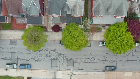 Top down aerial of city street in USA. Car pulls out of space and slowly drives on urban street. Church building at intersection.