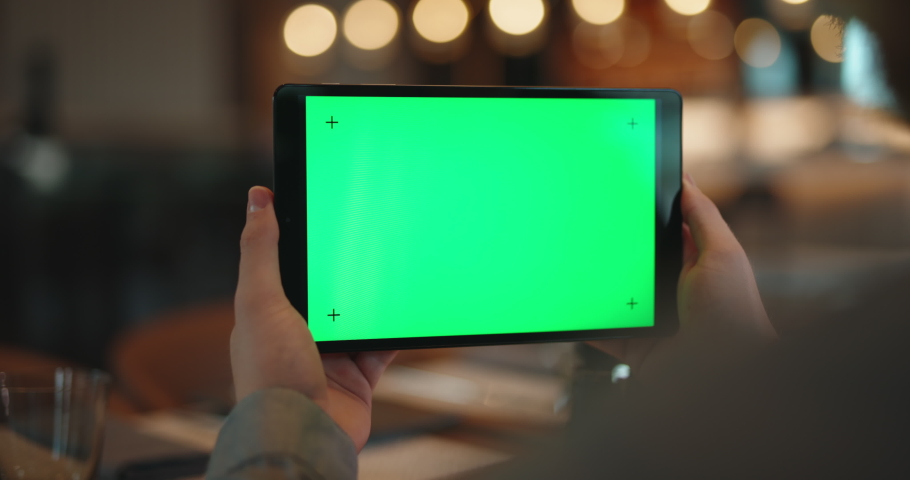 Close up shot of hands of man holding a tablet computer with green chroma key screen. Guy watching a video or having an online chat in cafe - always online 4k template footage Royalty-Free Stock Footage #1073122094