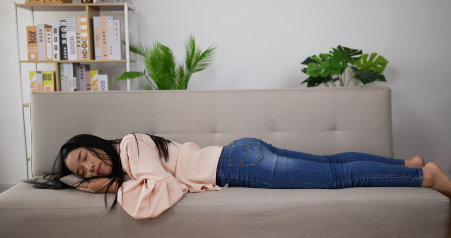 Asian woman walking to couch and sleep on the sofa with exhaustion. Exhausted or bored sleepy woman falls down on sofa. Asian tired teenage girl sleeping on sofa. | Shutterstock HD Video #1073123903